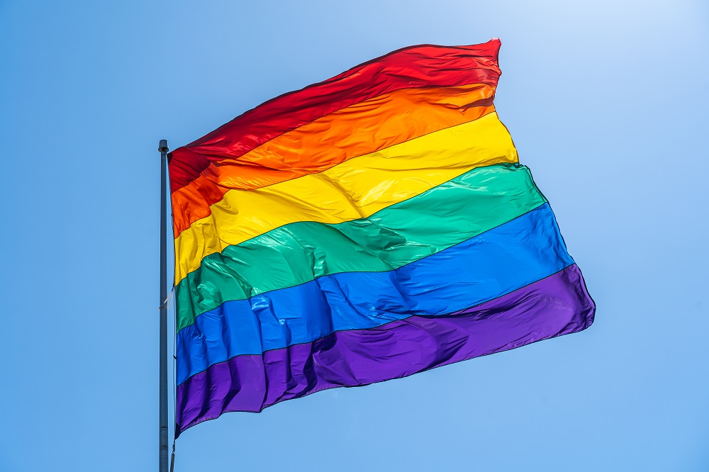 Rainbow gay pride flag on a blue sky