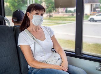Adult woman in a protective mask rides alone in an empty on public transport in the city. Social distance. Bus passengers are protected from the coronavirus. New normal. lifestyle during the pandemic