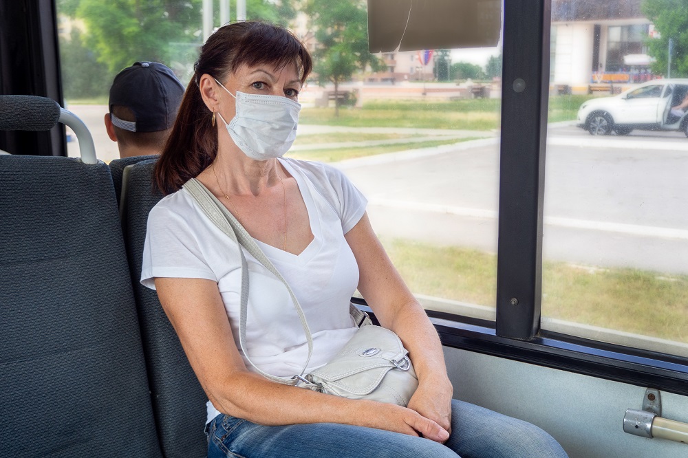 Adult woman in a protective mask rides alone in an empty on public transport in the city. Social distance. Bus passengers are protected from the coronavirus. New normal. lifestyle during the pandemic