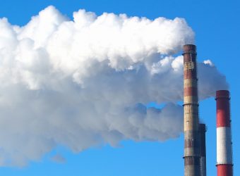 White smoke comes from pipes against blue sky