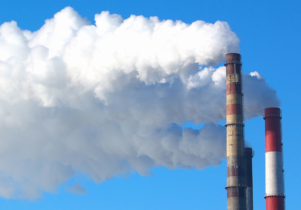 White smoke comes from pipes against blue sky