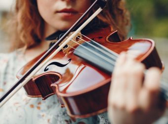 Beautiful girl in a summer park with a violin