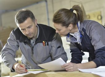 Workers measuring wood plank