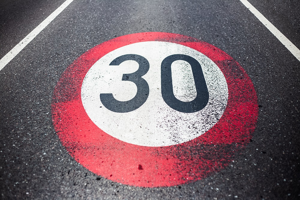 30km/h speed limit sign painted on asphalting road.