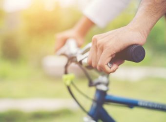 Close Up on biking man hands on the blurred nature sunrise backg