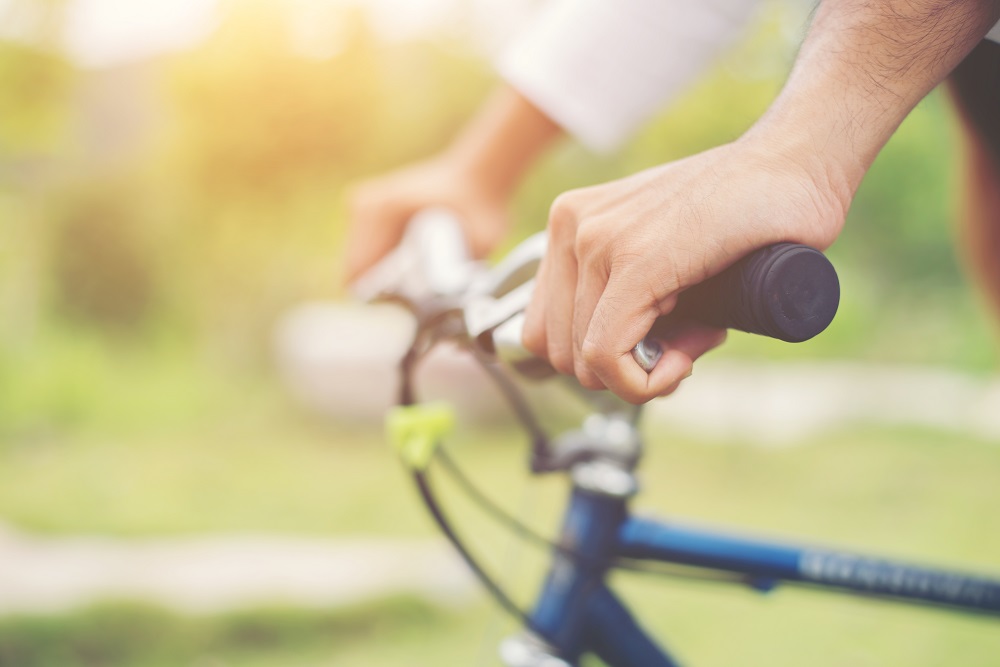 Close Up on biking man hands on the blurred nature sunrise backg