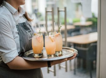 Closeup shot of a waiter serving cocktail with fresh oranges on a silver tray