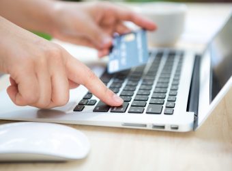 Hands holding a credit card and using laptop computer for online