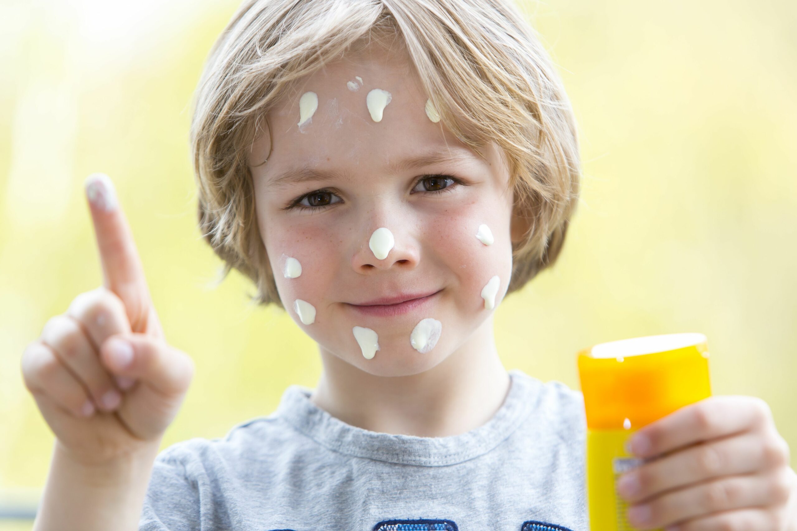 Kleiner Junge trägt sich selber Sonnencreme auf.