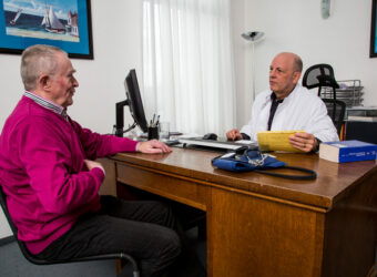 Arztpraxis, älterer Patient im Gespräch mit seinem Hausarzt