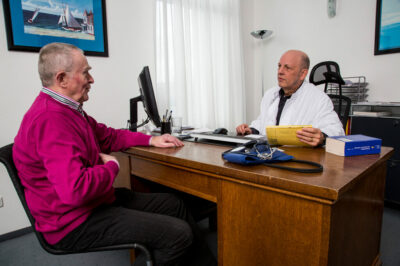 Arztpraxis, älterer Patient im Gespräch mit seinem Hausarzt