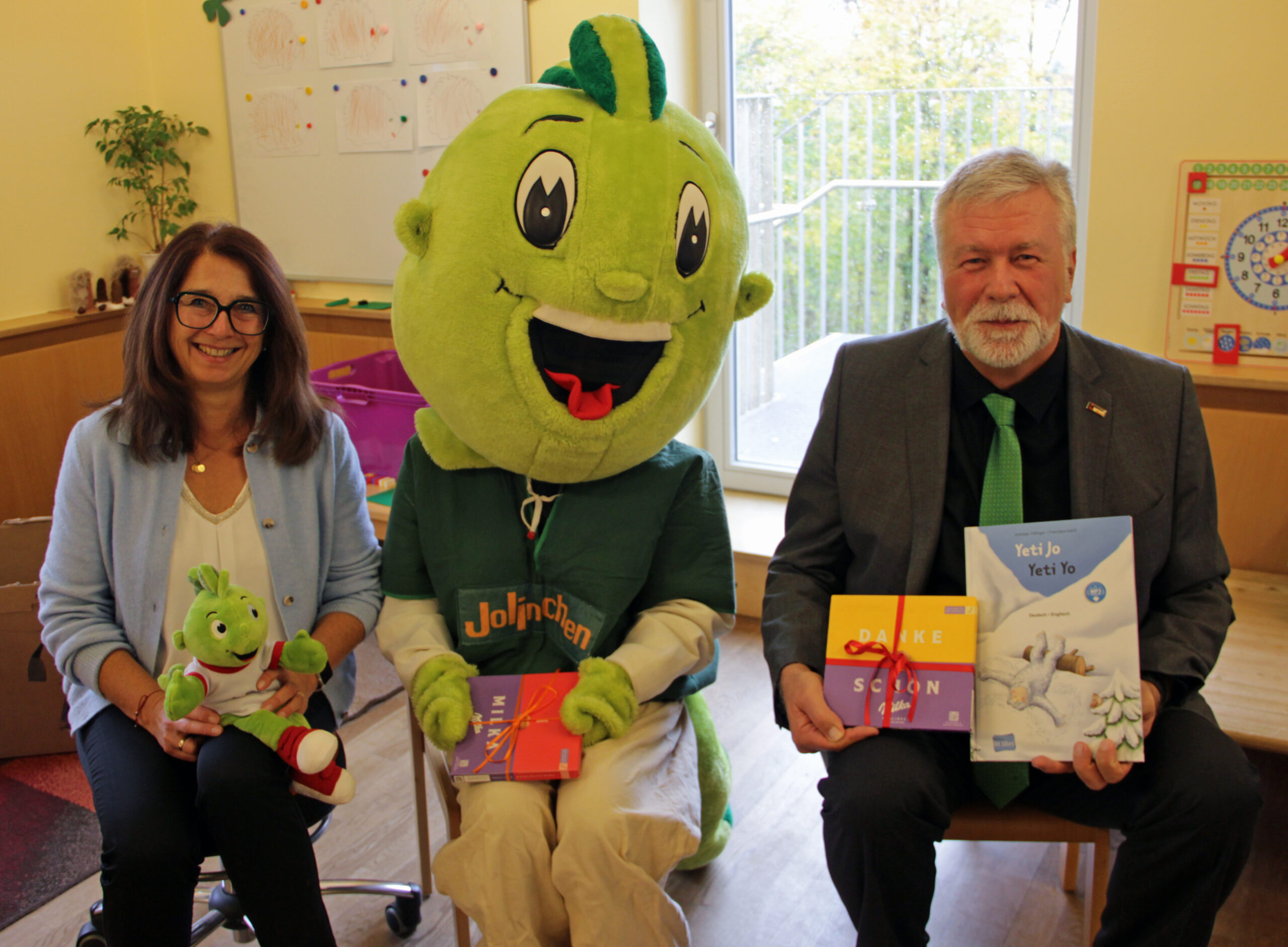 Kindergartenleiterin Claudia Klas und Ewald Kommer mit dem AOK-Maskottchen Jolinchen beim Vorlesetag im Kindergarten in Brunnen. Urhebervermerk: Rainer Stegmayr